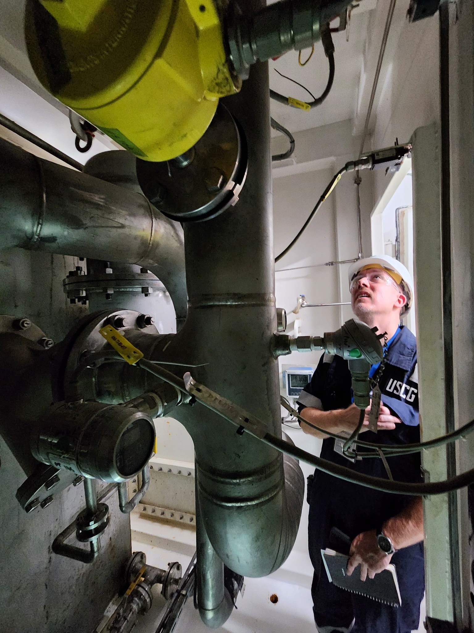 Staff engineer looking at piping onboard a vessel.
